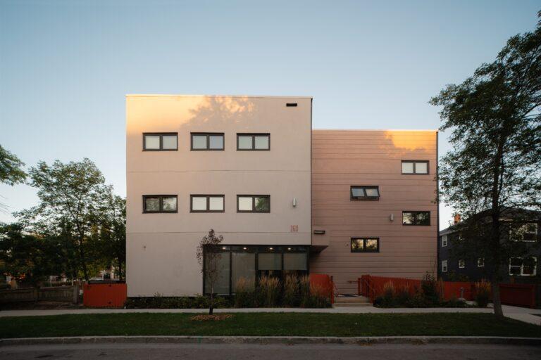 3 storey apartment building with picket fence .